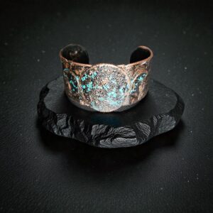 Solo product shot of the small Blue Moon Triple Goddess cuff on purple velvet, showcasing the hand-forged texture and deep midnight blue patina.