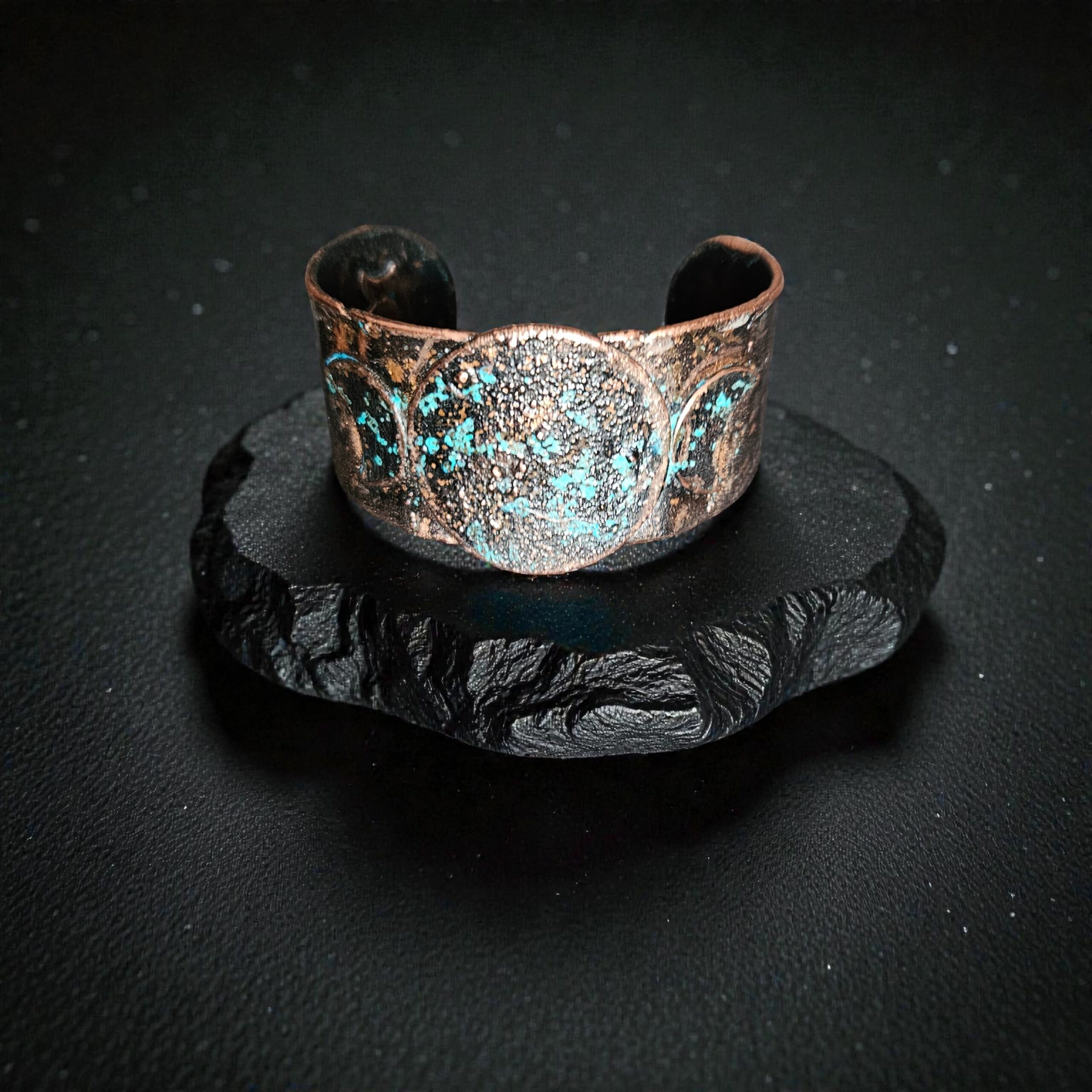 Solo product shot of the small Blue Moon Triple Goddess cuff on purple velvet, showcasing the hand-forged texture and deep midnight blue patina.