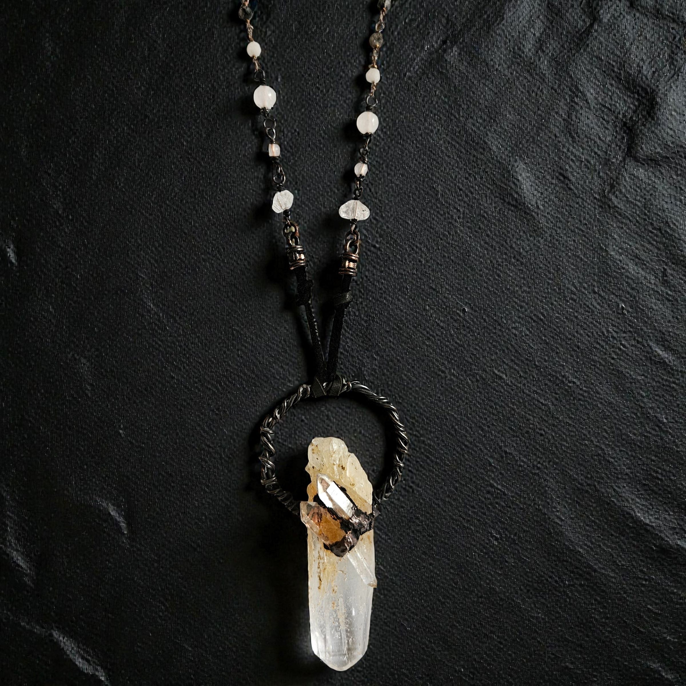 A top-down view of the "Monolith" talisman, showing the rugged, dark-patina copper armoring that secures the four distinct quartz points.