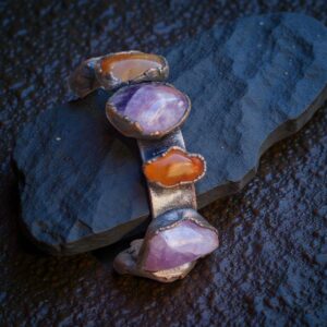 The Alchemist's Ember Cuff Bracelet featuring Carnelian and Amethyst shown on a dark background