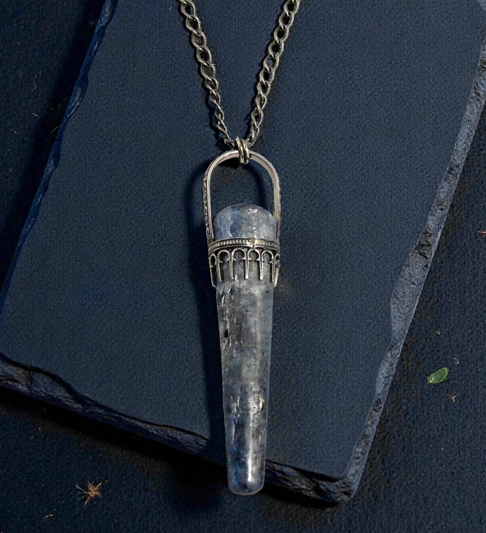 Blue Kyanite sceptor necklace set in sterling silver photographed on a black slate background.