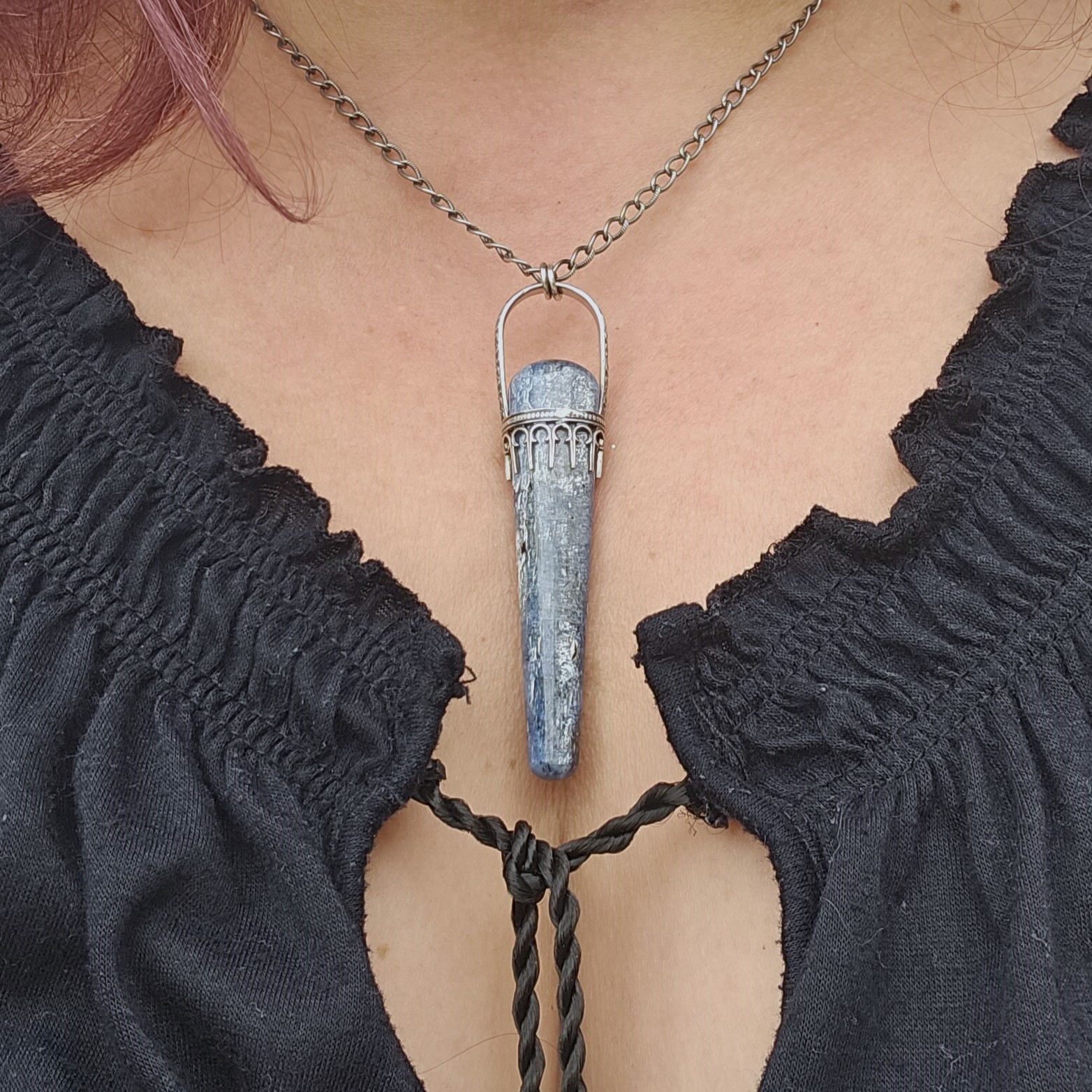 A blue kyanite and sterling silver pendant necklace shown on a model.