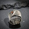 A rugged, ancient-style sterling silver moon ring with mixed metal copper accents on a rustic background