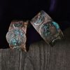 Hand-forged copper Triple Moon cuffs with a midnight blue patina on a background of dark wood and purple velvet.