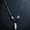 Lemurian quartz point with hand linked beaded chain shown on a black background