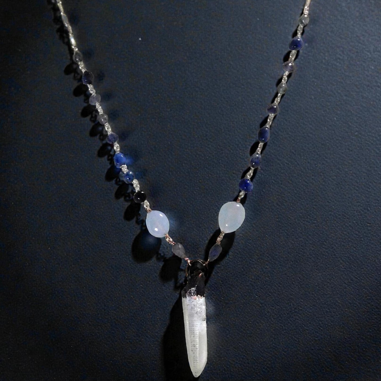 Lemurian quartz point with hand linked beaded chain shown on a black background