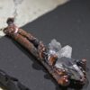 Close-up of "The Sticks and Stones" pendant showing the detailed copper-plated boxwood branches and a multi-point master healer quartz crystal.