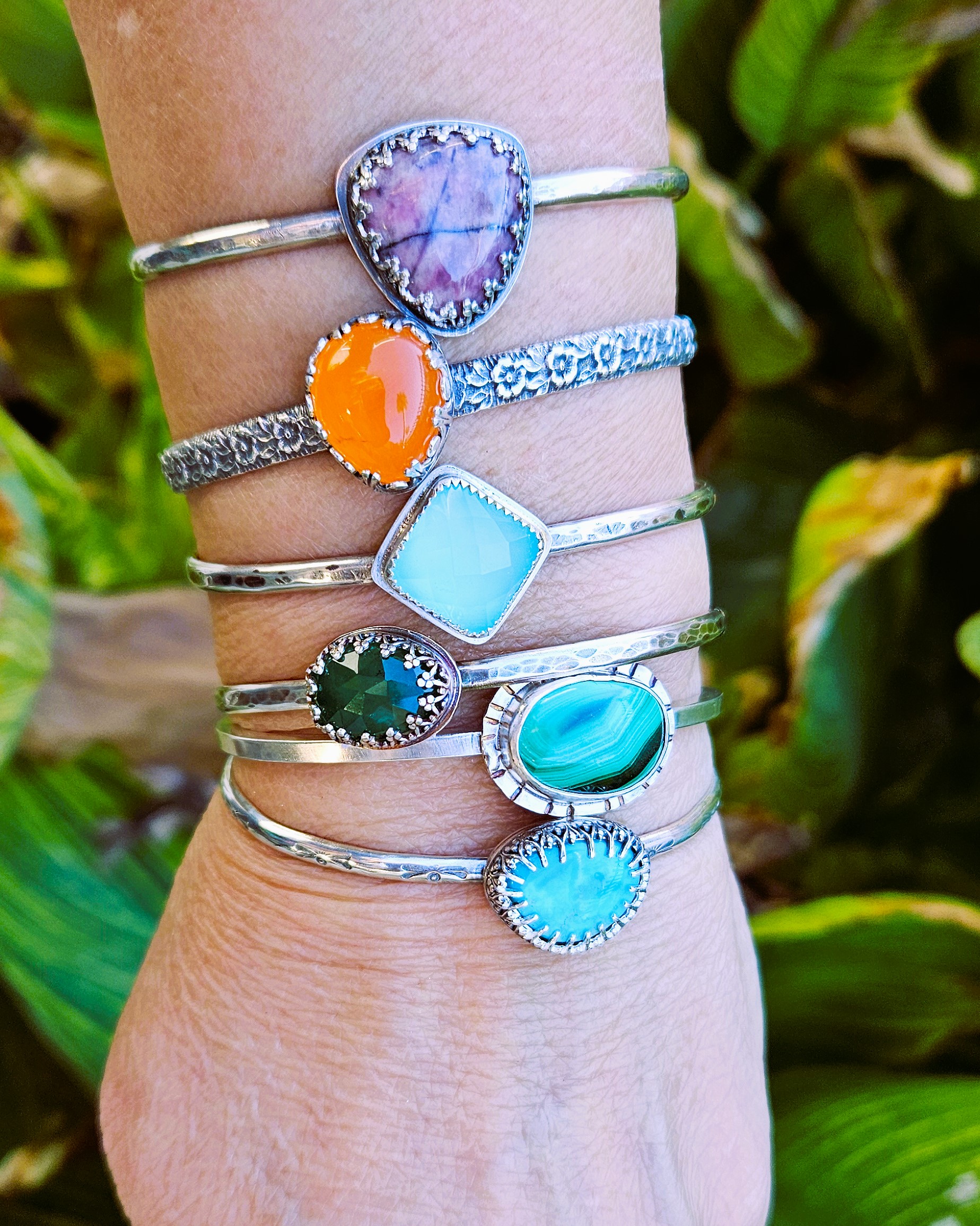 Sterling Silver and gemstone stack of cuff bracelets on models arm.