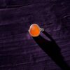 Close up view of a rosecut carnelian ring set in sterling silver on a dark purple wood background