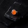 Close up view of a rosecut carnelian ring set in sterling silver on a black slate background