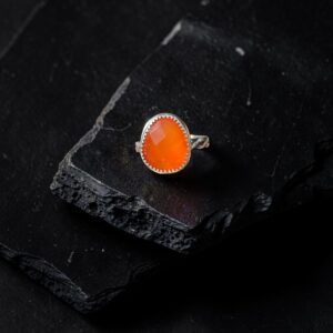 Close up view of a rosecut carnelian ring set in sterling silver on a black slate background