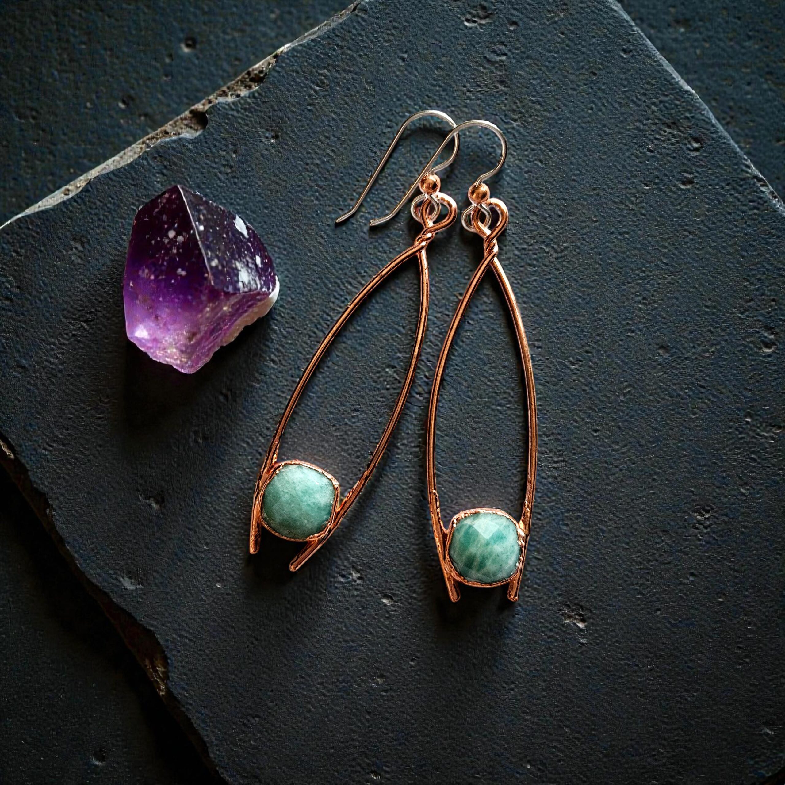 Close-up of the raw aquamarine stones, showing the intricate, dark-patina copper armor and the sterling silver earwire accents.