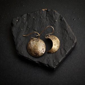 Asymmetrical Merlin's Gold earrings featuring one hand-stamped full moon and one crescent moon with a dark, antiqued finish.