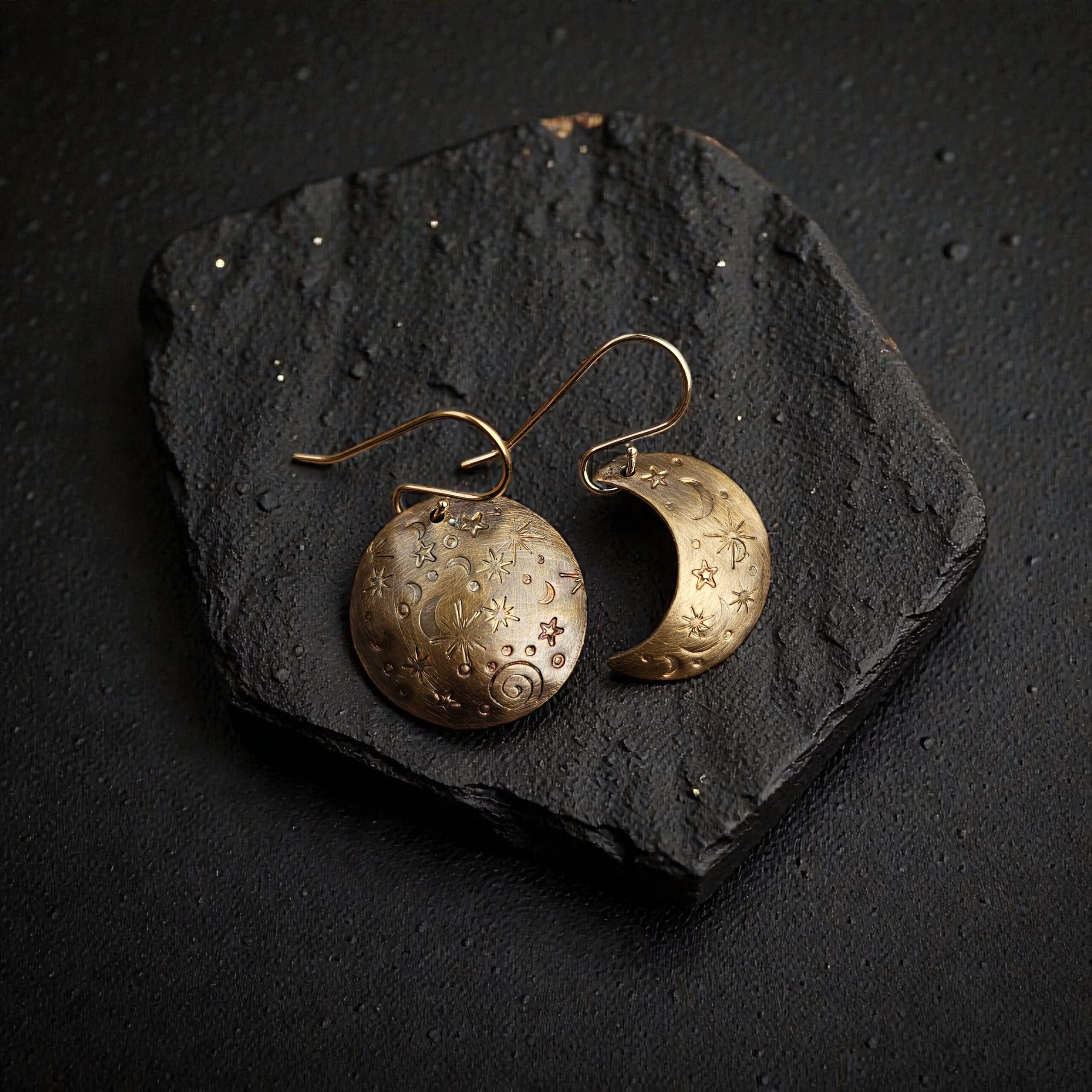 Asymmetrical Merlin's Gold earrings featuring one hand-stamped full moon and one crescent moon with a dark, antiqued finish.