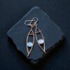 A pair of polished copper electroformed drop earrings with flashy blue moonstone cabochons.