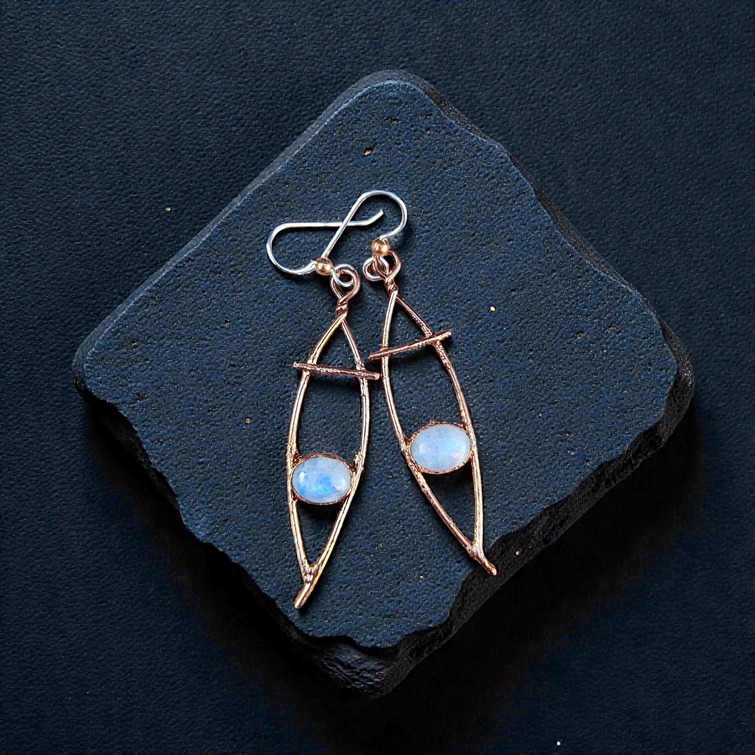 A pair of polished copper electroformed drop earrings with flashy blue moonstone cabochons.