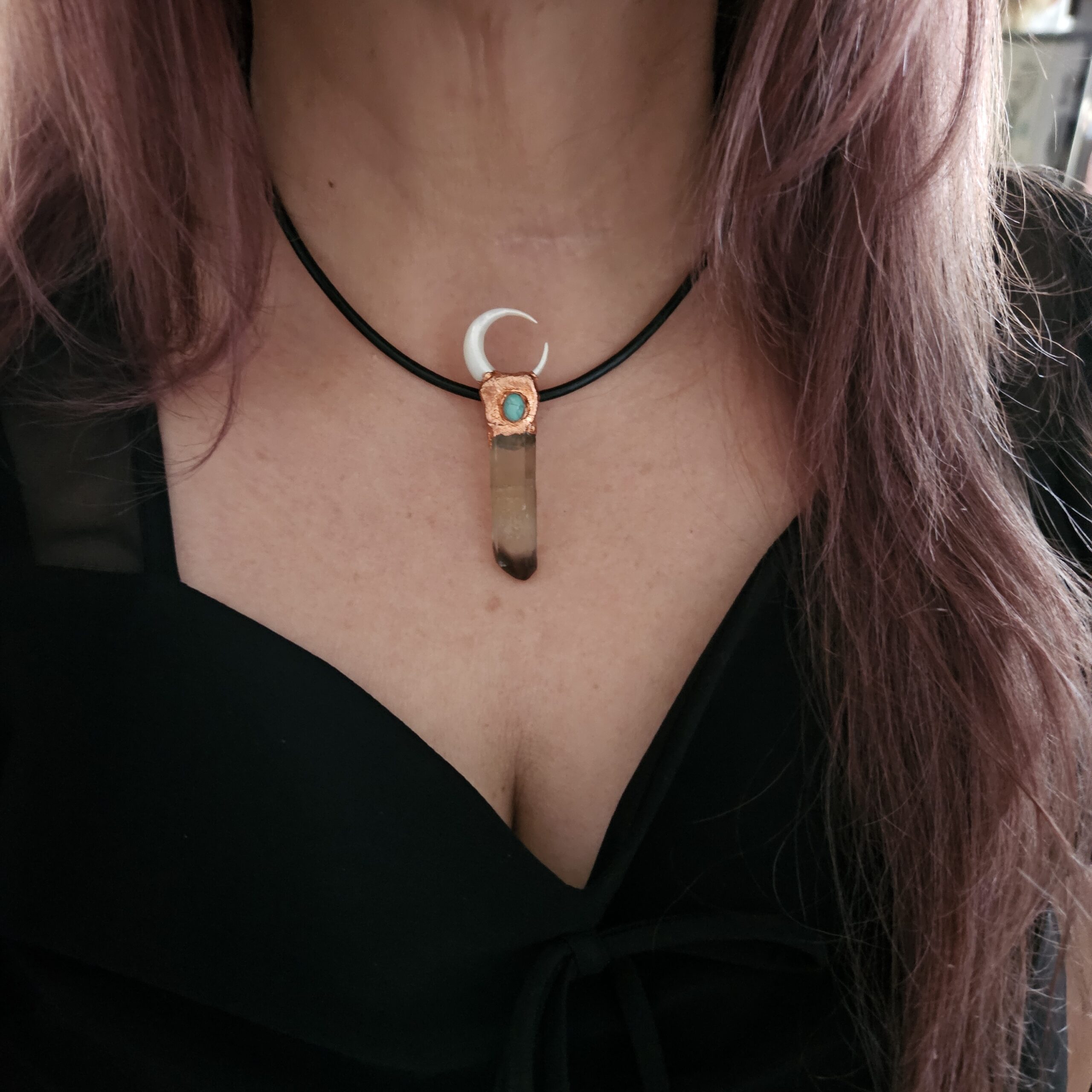 A tall, rectangular Smoky Quartz crystal pendant with an elk bone crescent moon and turquoise accent, worn as a choker on a black cord against a black top.