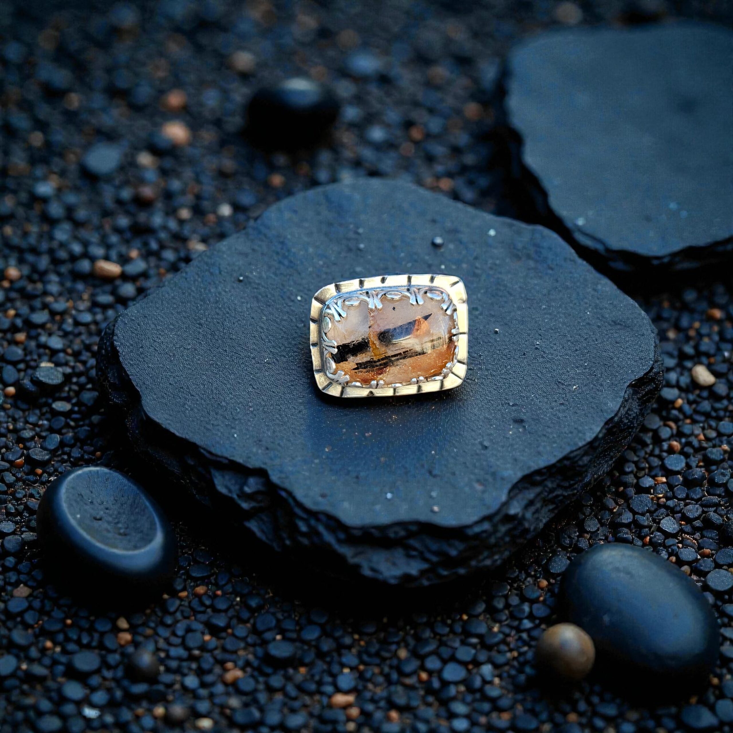 A rectangular Tourmalinated Quartz ring with black needles and red iron oxide set in a sterling silver bezel.