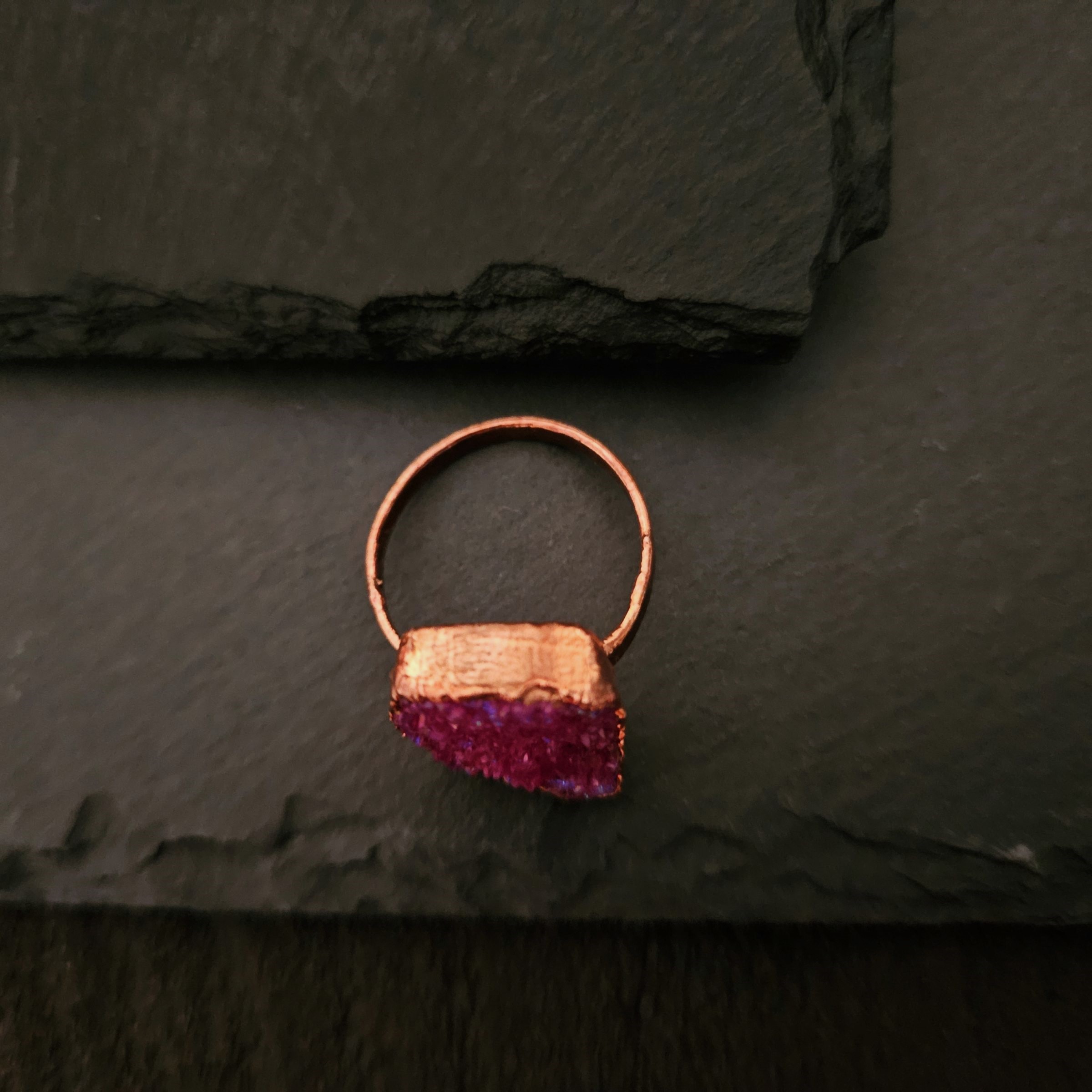 Top-down view of a copper electroformed ring band and the thick setting of a pink druzy stone.