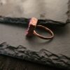Profile of a hand-sculpted copper ring showing the textured band and the height of the pink druzy setting.