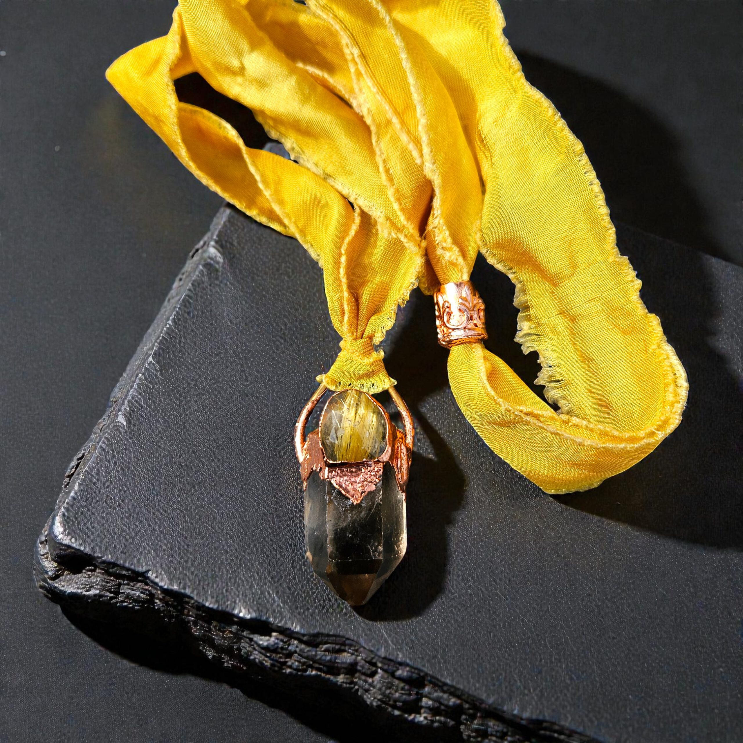 Large smoky quartz point topped with a rutile quartz cabochon in a shiny copper electroformed setting, suspended on a frayed-edge golden silk ribbon.