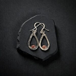 Artisan hammered sterling silver earrings with pink tourmaline cabochons displayed on a rugged black slate fragment.