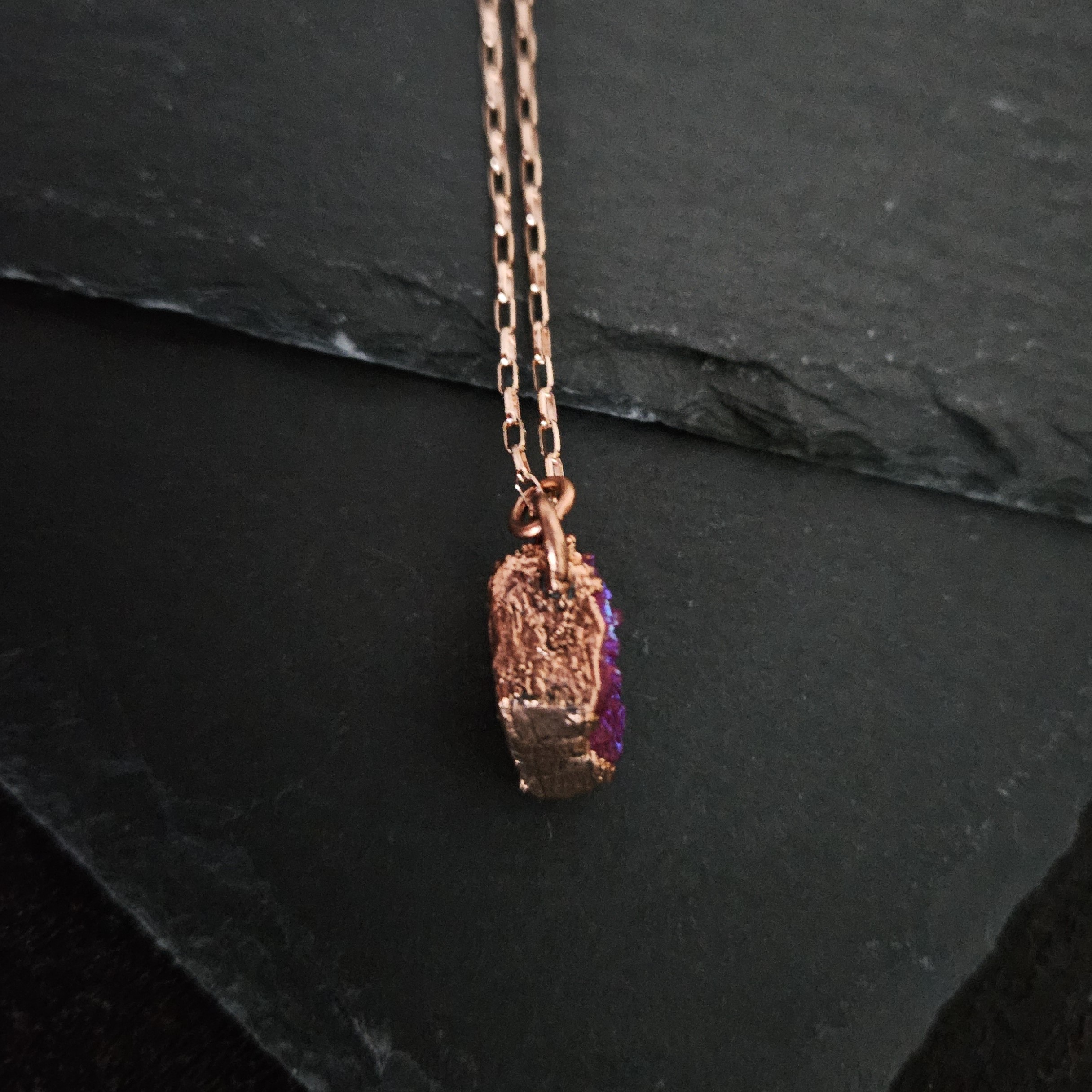 Side view of a thick, sculptural copper electroformed setting for a pink druzy pendant, highlighting the artisan metalwork.