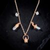 A copper charm necklace featuring a bubbling cauldron with pink spinel, herkimer diamonds, and clear quartz