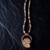 High-contrast overhead view highlighting the intricate, textured copper metalwork framing the natural chambers of the cut ammonite fossil and its vibrant multi-gemstone accent strand.