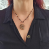 Medium shot of the ammonite fossil talisman worn against a black shirt, demonstrating how the 18-inch natural gemstone beaded chain drapes gracefully along the neckline, accentuating the substantial weight and centerpiece scale of the focal pendant.
