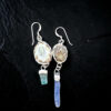 flat-lay photograph on a dark slate background showing the reverse side of the earrings, revealing the natural, rustic brown striated pattern of the genuine limpet shells bound in textured silver metalwork.