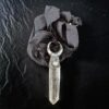 A high-contrast flat lay showcasing the pendant nestled against the coiled, hand-dyed black silk ribbon, emphasizing the deep obsidian color of the fabric against the brilliant clarity of the crystal.