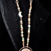 Macro photograph focusing on the asymmetrical bead layout, highlighting the luminous white mother-of-pearl crescent moon charm nested among earth-toned, faceted gemstone beads and metallic accents.