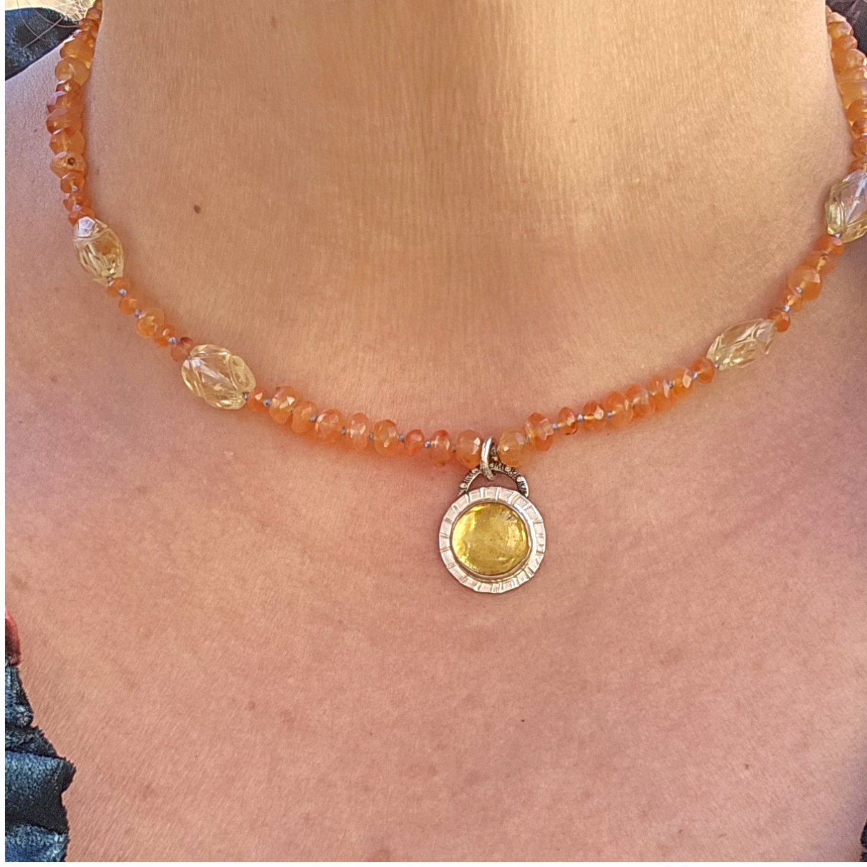 Model wearing the 16-inch golden amber amulet, showing the collar-length drop of the carnelian strand and round silver pendant on the chest.