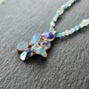 Macro view of the textured copper electroformed crystal cluster pendant lying on dark gray textured slate, capturing the natural facets of raw apatite and kyanite.