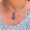 Model wearing the 16.5-inch Sky Realm blue crystal cluster necklace over a light blue ruffled top, showing where the multi-gemstone pendant falls near the collarbone.