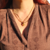 Model wearing the Earth's Veil Amulet with a double-layered Tunduru tourmaline bead strand resting over a earthy brown embroidered top.